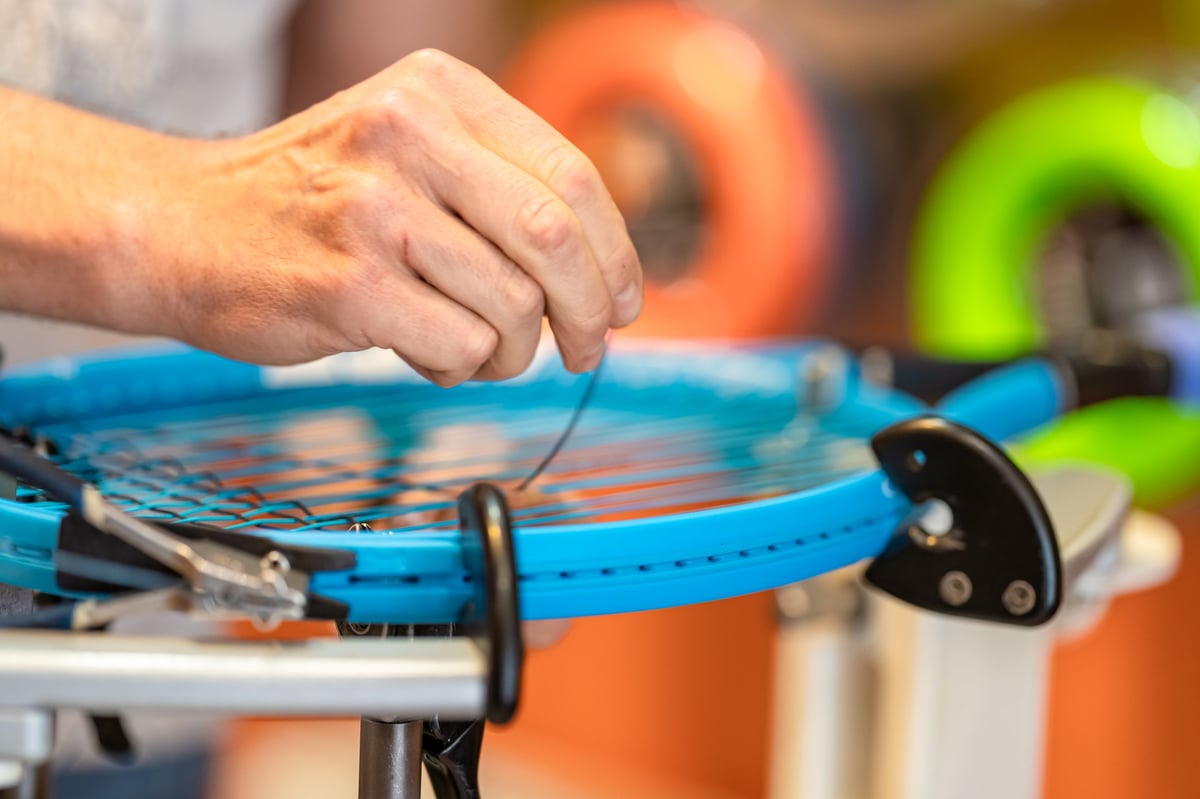 Technician manually stringing a tennis racket